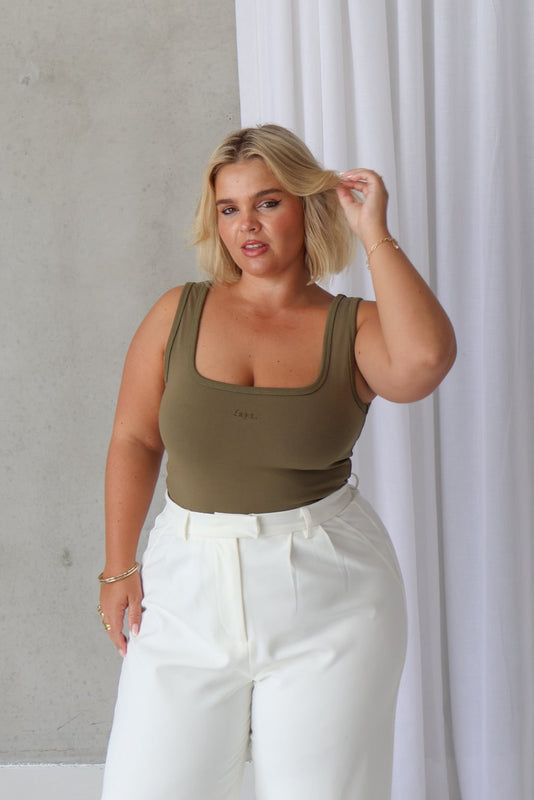 A model wearing a green square neckline tank top with thick straps, made from a buttery soft, double-lined fabric.